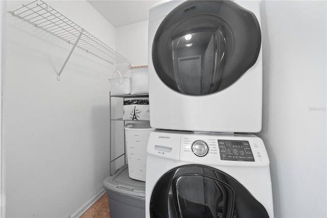 3203 Herons Point Cir, Kissimmee, FL 34741 - laundry area featuring stacked washer and clothes dryer, tile patterned floors, and baseboards