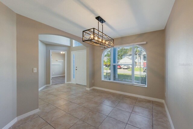 12303 Bohannon Blvd, Orlando, FL 32824 - unfurnished dining area featuring arched walkways, light tile patterned floors, a chandelier, and baseboards
