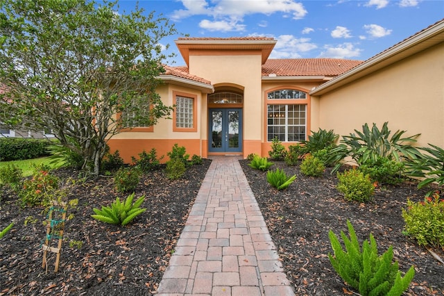 517 Milano Rd, Poinciana, FL 34759 - view of exterior entry featuring french doors, stucco siding, and a tiled roof