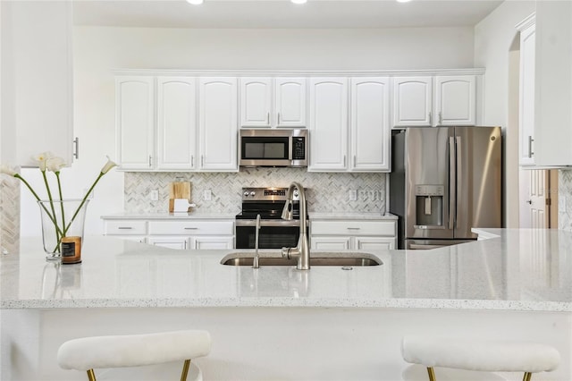 517 Milano Rd, Poinciana, FL 34759 - kitchen featuring stainless steel appliances, a sink, white cabinetry, light stone countertops, and recessed lighting