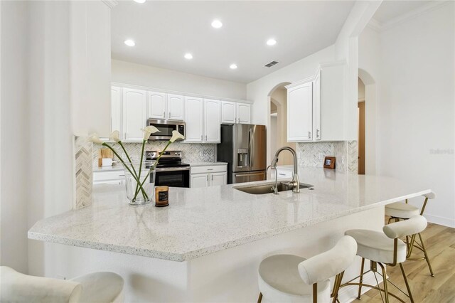 517 Milano Rd, Poinciana, FL 34759 - kitchen with appliances with stainless steel finishes, a sink, a peninsula, arched walkways, and light stone counters