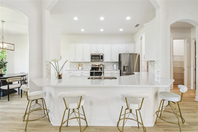 517 Milano Rd, Poinciana, FL 34759 - kitchen with stainless steel appliances, a sink, arched walkways, backsplash, and a kitchen breakfast bar
