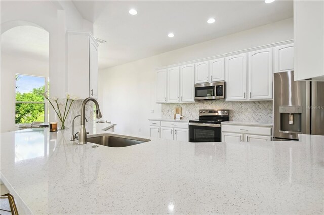 517 Milano Rd, Poinciana, FL 34759 - kitchen with appliances with stainless steel finishes, a sink, arched walkways, tasteful backsplash, and white cabinets