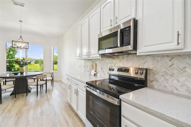 517 Milano Rd, Poinciana, FL 34759 - kitchen featuring appliances with stainless steel finishes, backsplash, white cabinetry, a chandelier, and light stone counters