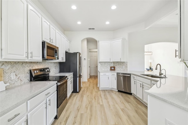 517 Milano Rd, Poinciana, FL 34759 - kitchen with stainless steel appliances, a sink, arched walkways, white cabinets, and tasteful backsplash