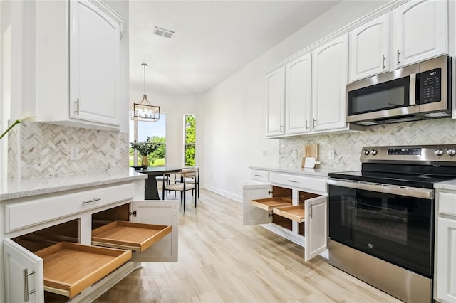 517 Milano Rd, Poinciana, FL 34759 - kitchen featuring appliances with stainless steel finishes, white cabinetry, decorative backsplash, light wood-style floors, and baseboards