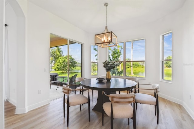 517 Milano Rd, Poinciana, FL 34759 - dining space featuring light wood-type flooring, a chandelier, baseboards, and arched walkways