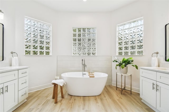 517 Milano Rd, Poinciana, FL 34759 - full bath featuring a freestanding bath, wood finished floors, two vanities, and baseboards