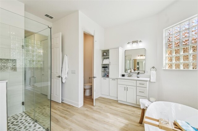 517 Milano Rd, Poinciana, FL 34759 - full bathroom with a shower stall, wood finished floors, toilet, vanity, and a freestanding tub