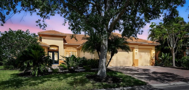 517 Milano Rd, Poinciana, FL 34759 - mediterranean / spanish-style house with a garage, driveway, stucco siding, and a tile roof