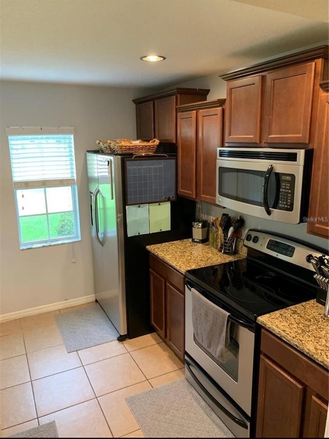 9871 Trumpet Vine Loop, Trinity, FL 34655 - kitchen with appliances with stainless steel finishes, light tile patterned floors, light stone countertops, baseboards, and recessed lighting