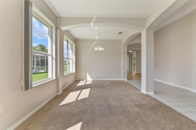 unfurnished dining area featuring carpet flooring, arched walkways, baseboards, tile patterned floors, and a ceiling fan
