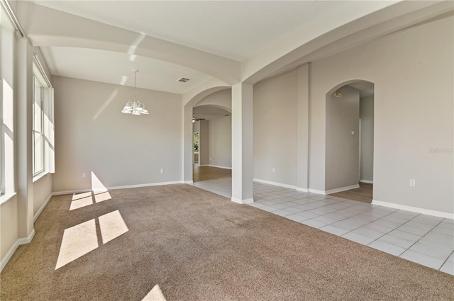 carpeted empty room with arched walkways, tile patterned flooring, and baseboards