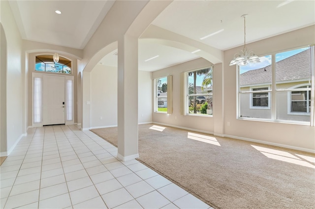 foyer entrance featuring arched walkways, healthy amount of natural light, and a chandelier