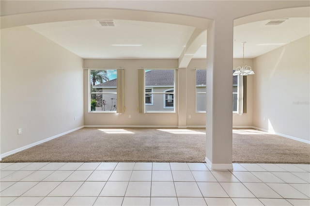 spare room with light colored carpet, a chandelier, baseboards, and arched walkways