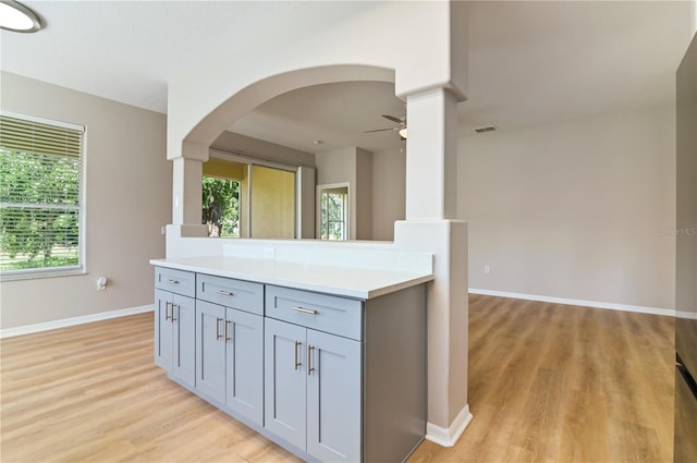 kitchen with a ceiling fan, light countertops, light wood-type flooring, gray cabinetry, and baseboards