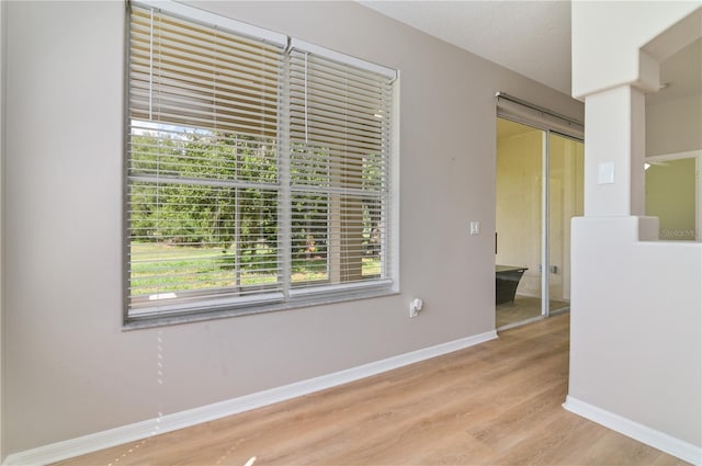 empty room featuring light wood-type flooring, plenty of natural light, and baseboards
