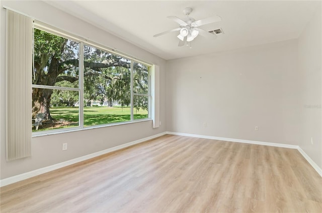 spare room featuring healthy amount of natural light, light wood-type flooring, ceiling fan, and baseboards