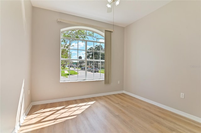 empty room featuring wood finished floors, baseboards, and a ceiling fan
