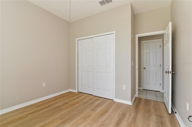 unfurnished bedroom with light wood finished floors, a closet, and baseboards