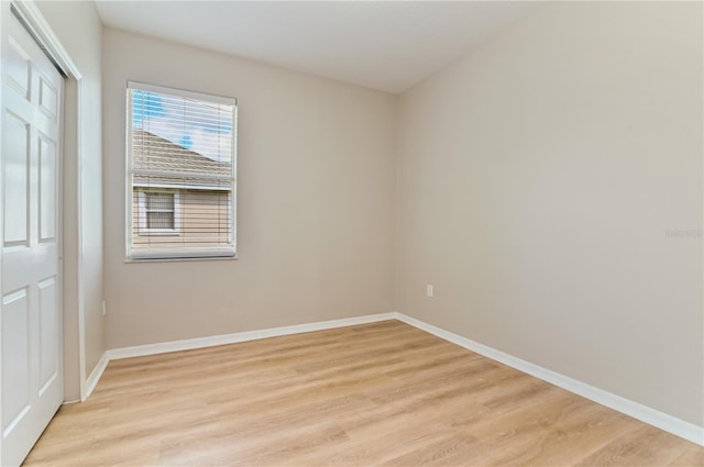 unfurnished bedroom featuring light wood-style flooring, baseboards, and a closet