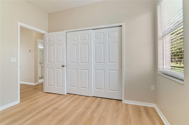 unfurnished bedroom with light wood-style floors, baseboards, and a closet
