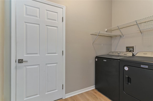 clothes washing area with washer and dryer, baseboards, and light wood-type flooring