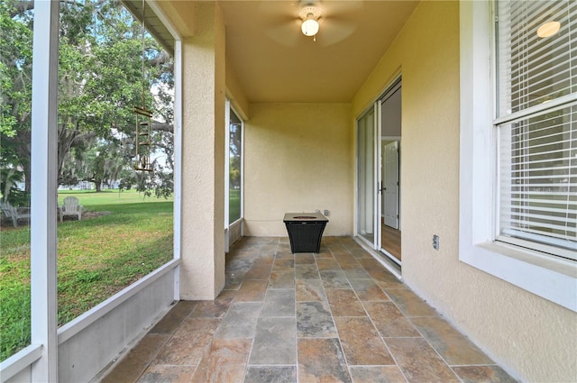 unfurnished sunroom with ceiling fan