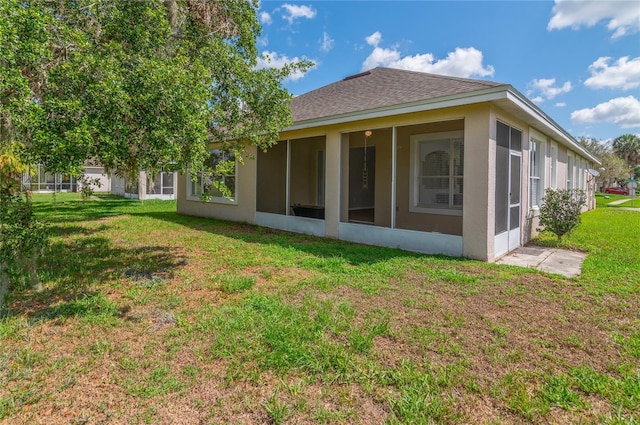 back of property featuring a sunroom, a lawn, and roof with shingles