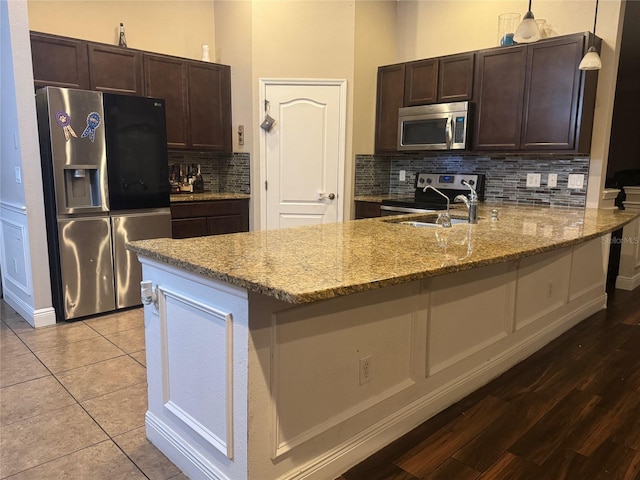 18805 Nettleton St, Orlando, FL 32833 - kitchen featuring appliances with stainless steel finishes, a peninsula, light stone countertops, and dark brown cabinetry
