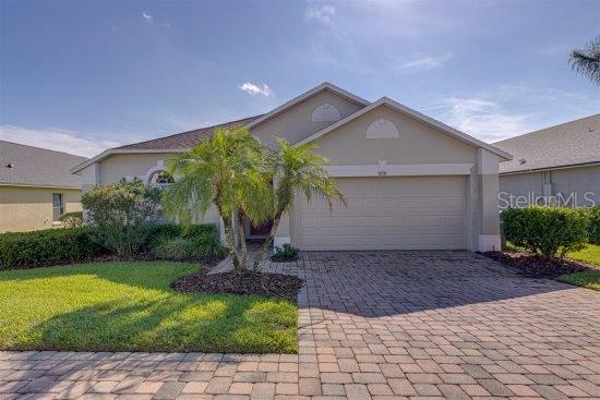 926 Balmoral Dr, Davenport, FL 33896 - view of front facade featuring decorative driveway, an attached garage, stucco siding, and a front lawn