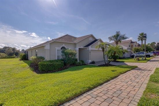 926 Balmoral Dr, Davenport, FL 33896 - view of side of home with a yard, stucco siding, and decorative driveway