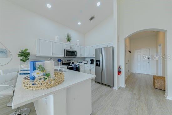 926 Balmoral Dr, Davenport, FL 33896 - kitchen featuring appliances with stainless steel finishes, arched walkways, high vaulted ceiling, a peninsula, and light countertops