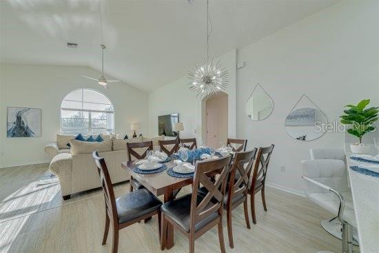 926 Balmoral Dr, Davenport, FL 33896 - dining room featuring vaulted ceiling, light wood-type flooring, ceiling fan, baseboards, and a chandelier