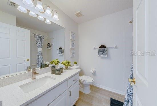 926 Balmoral Dr, Davenport, FL 33896 - bathroom featuring toilet, wood finished floors, baseboards, vanity, and a shower with shower curtain