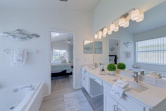 926 Balmoral Dr, Davenport, FL 33896 - full bathroom featuring ensuite bathroom, double vanity, a bath, wood finished floors, and ceiling fan