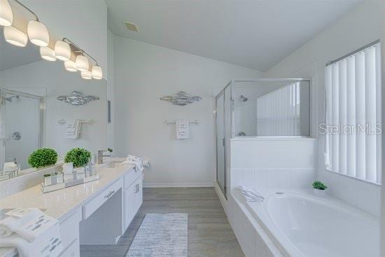 926 Balmoral Dr, Davenport, FL 33896 - full bath featuring a stall shower, lofted ceiling, vanity, a bath, and wood finished floors