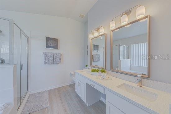 926 Balmoral Dr, Davenport, FL 33896 - full bathroom featuring lofted ceiling, a stall shower, wood finished floors, and double vanity