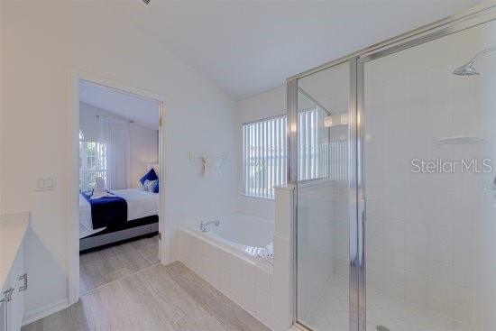 926 Balmoral Dr, Davenport, FL 33896 - ensuite bathroom with a bath, a stall shower, vaulted ceiling, wood finished floors, and vanity