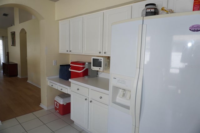 10308 Soaring Eagle Dr, Riverview, FL 33578 - kitchen with white refrigerator with ice dispenser, arched walkways, white cabinetry, light countertops, and light tile patterned flooring