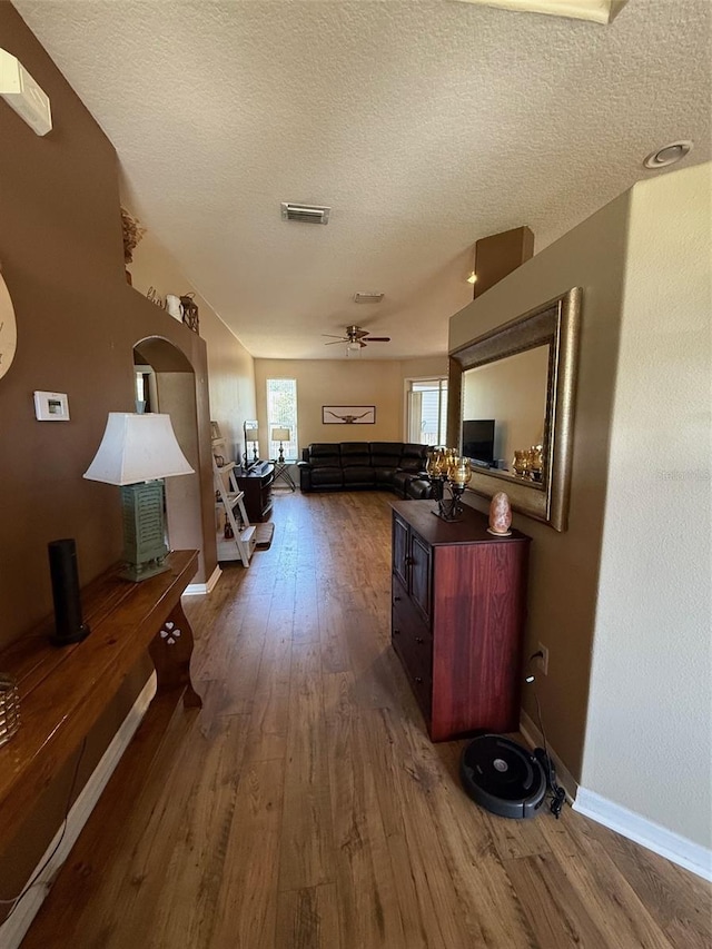 hall with wood finished floors, a textured ceiling, and baseboards