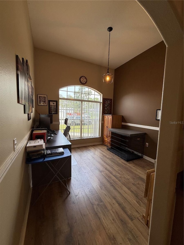 office area featuring wood finished floors, baseboards, and arched walkways