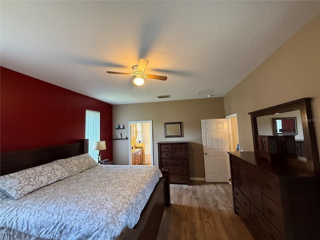 bedroom with wood finished floors, ceiling fan, and ensuite bath