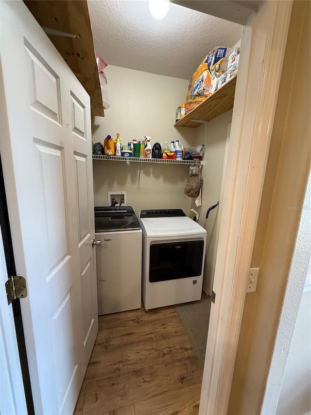 laundry room featuring washer and clothes dryer, a textured ceiling, and light wood-style flooring