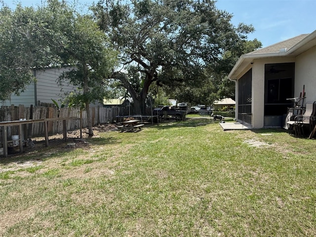 view of yard featuring a sunroom and ceiling fan