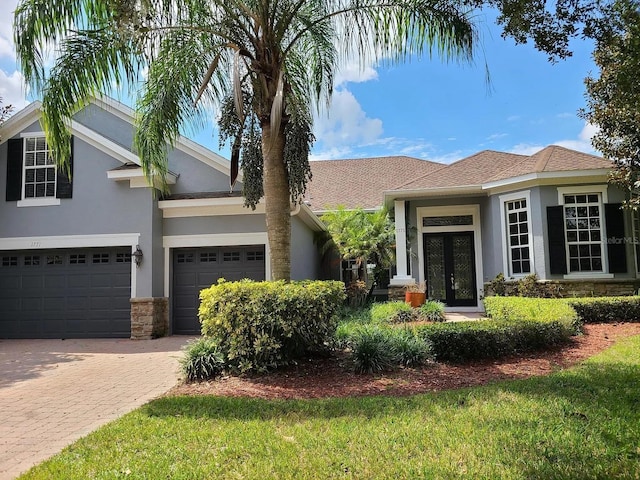 1771 Lee Janzen Dr, Kissimmee, FL 34744 - view of front of property featuring french doors, stucco siding, stone siding, decorative driveway, and a garage