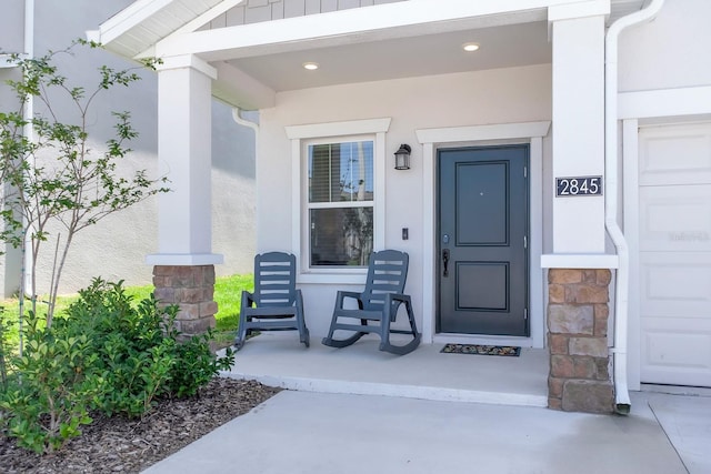 view of exterior entry featuring stucco siding and covered porch