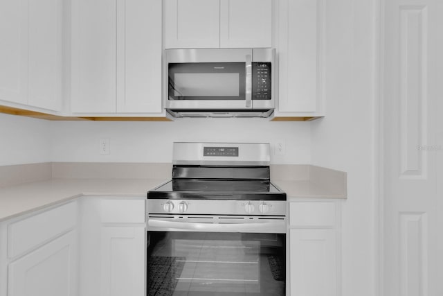 kitchen with stainless steel appliances, white cabinetry, and light countertops