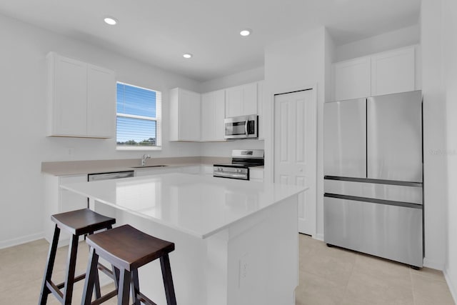 kitchen featuring stainless steel appliances, a kitchen breakfast bar, white cabinetry, a sink, and recessed lighting