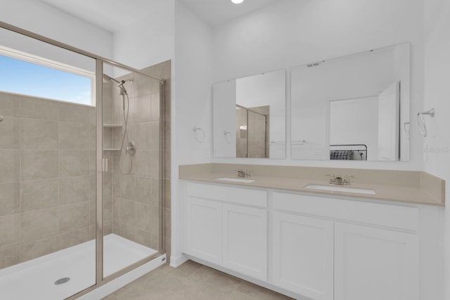 bathroom with a stall shower, double vanity, and tile patterned flooring